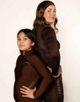 Young rider and adult rider wearing brown fleece lined base layer for horse riders.