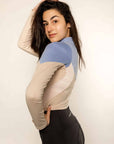 Model wearing a two tone equestrian base layer with 1/4 zip detail and mesh side panels with black riding leggings