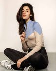 Model sitting down wearing a two tone equestrian base layer with 1/4 zip detail and mesh side panels.