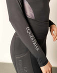 Model wearing charcoal grey riding leggings with pink and grey base layer top with white details.