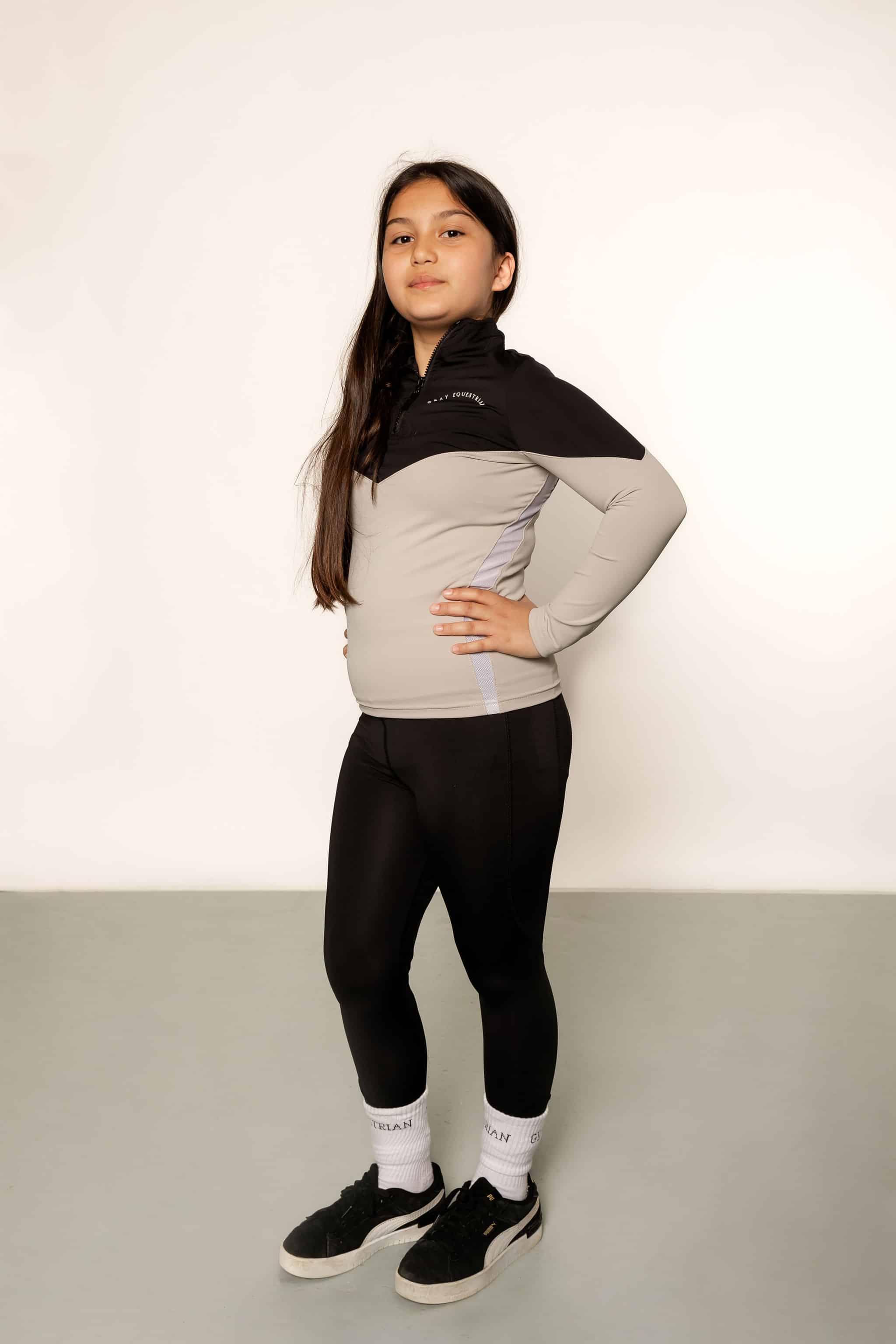 Our child model wearing our black and grey two toned base layer and black riding leggings.