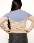 Young rider wearing blue and beige base layer with black leggings from behind