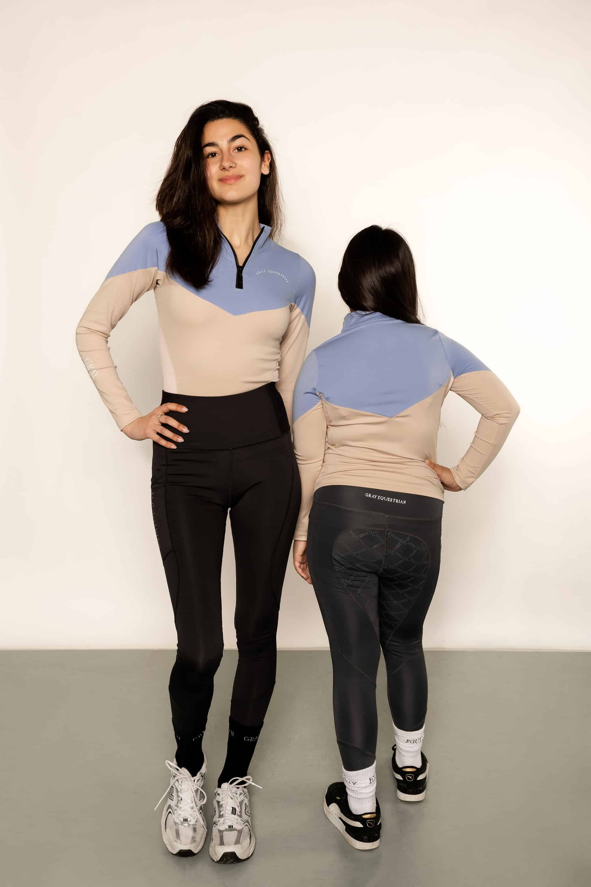 Adult rider and child rider wearing blue and beige base layers with leggings