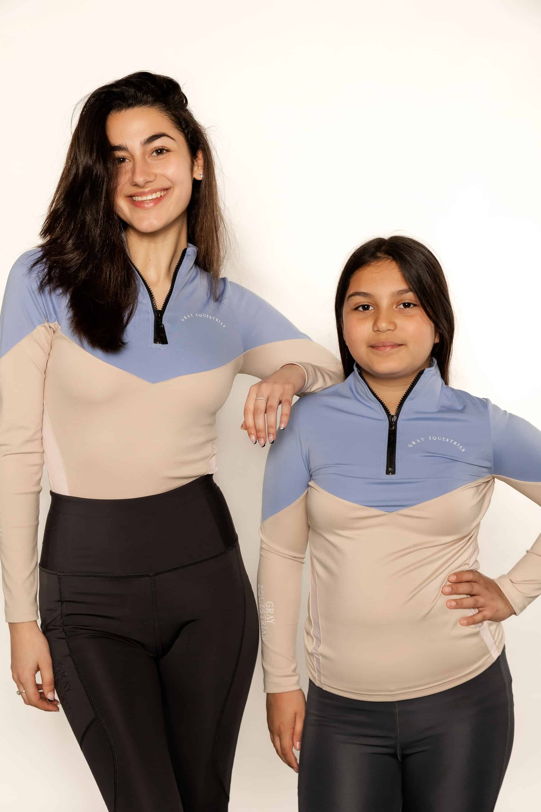 Young rider and adult model wearing beige and blue base layer and riding leggings