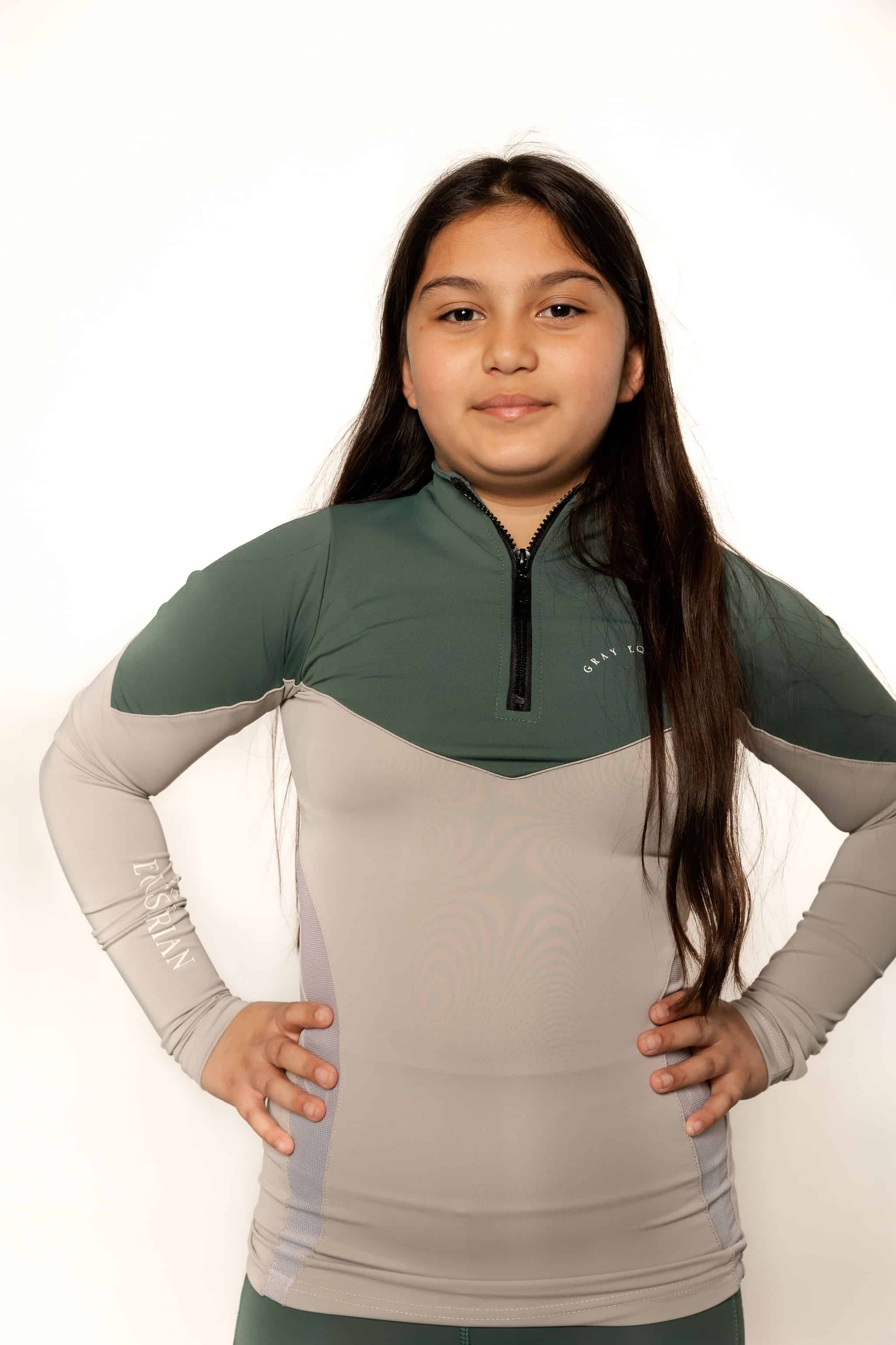 A child model wearing our our green and grey base layer with green leggings.