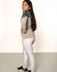 A child model wearing our our green and grey base layer with white leggings.
