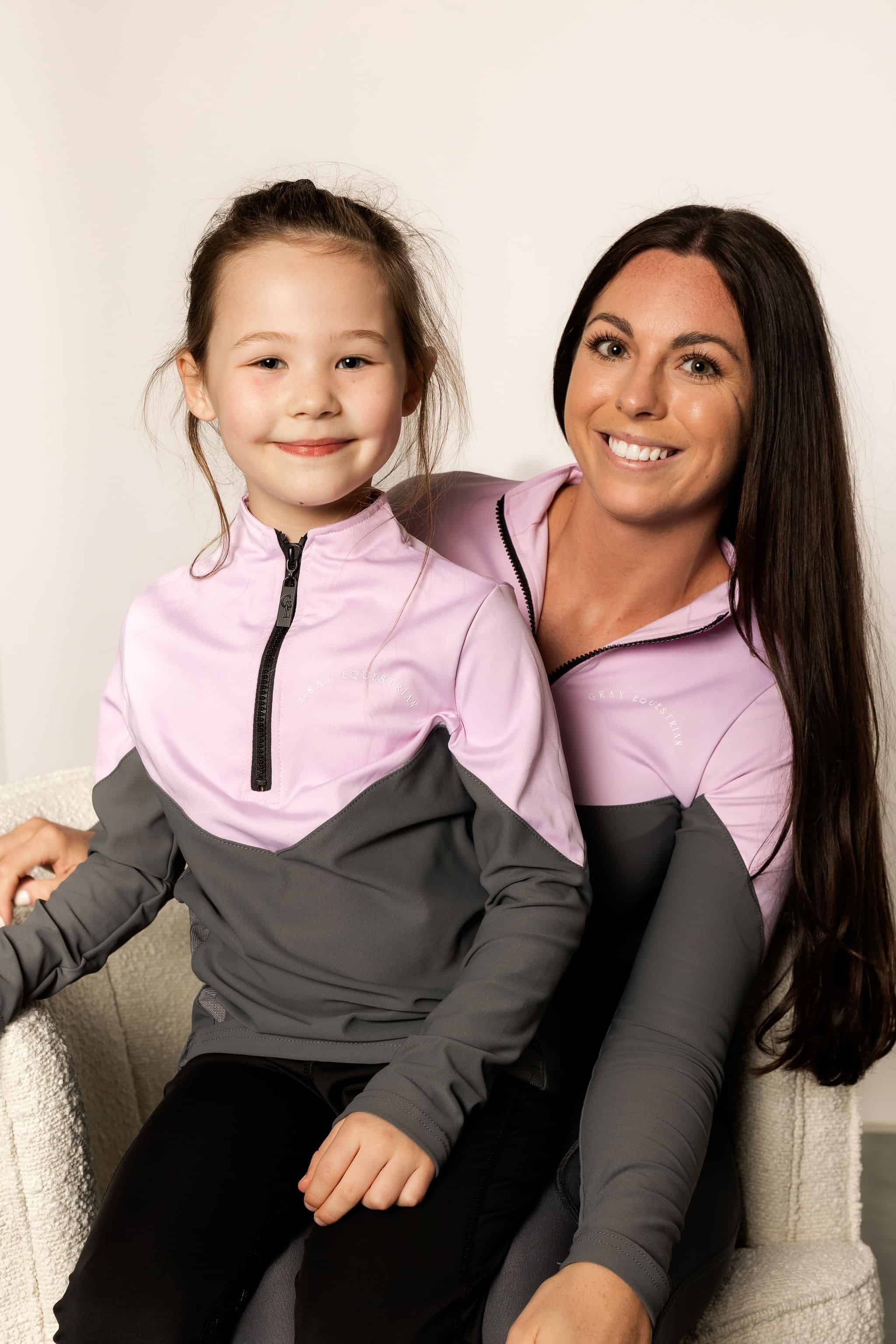 Young rider wearing lilac and grey base layer with adult rider