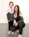 Young rider wearing lilac and grey base layer with adult rider bending down