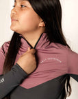 Young Rider holding 1/4 zip on pink and grey base layer