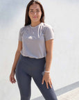 Brunette model wearing grey cotton t shirt with charcoal grey leggings.