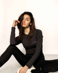 Brunette model wearing long sleeve equestrian lycra base layer top and black leggings sitting down