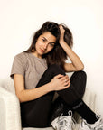 Model sitting in chair wearing grey t shirt and black leggings