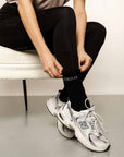 Model pulling up socks while sitting on chair