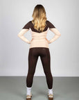 Model wearing a long sleeved brown and nude two toned base layer and brown equestrian leggings.