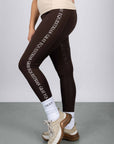 A model wearing our brown renew leggings with white Grey Equestrian branding down the side.
