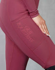 A close up of the gloss Grey Equestrian logo and phone pocket on our fleece-lined berry leggings.
