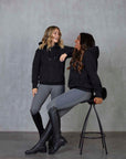 Two models standing side by side wearing our black fleece-lined oversized equestrian hoodie and grey riding leggings.