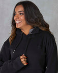 Brunette model wearing our black fleece-lined oversized equestrian hoodie and grey riding leggings.