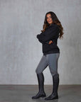 Brunette model wearing our black fleece-lined oversized equestrian hoodie and grey riding leggings.