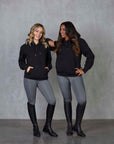 Two models standing side by side wearing our black fleece-lined oversized equestrian hoodie and grey riding leggings.