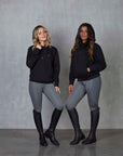 Two models standing side by side wearing our black fleece-lined oversized equestrian hoodie and grey riding leggings.