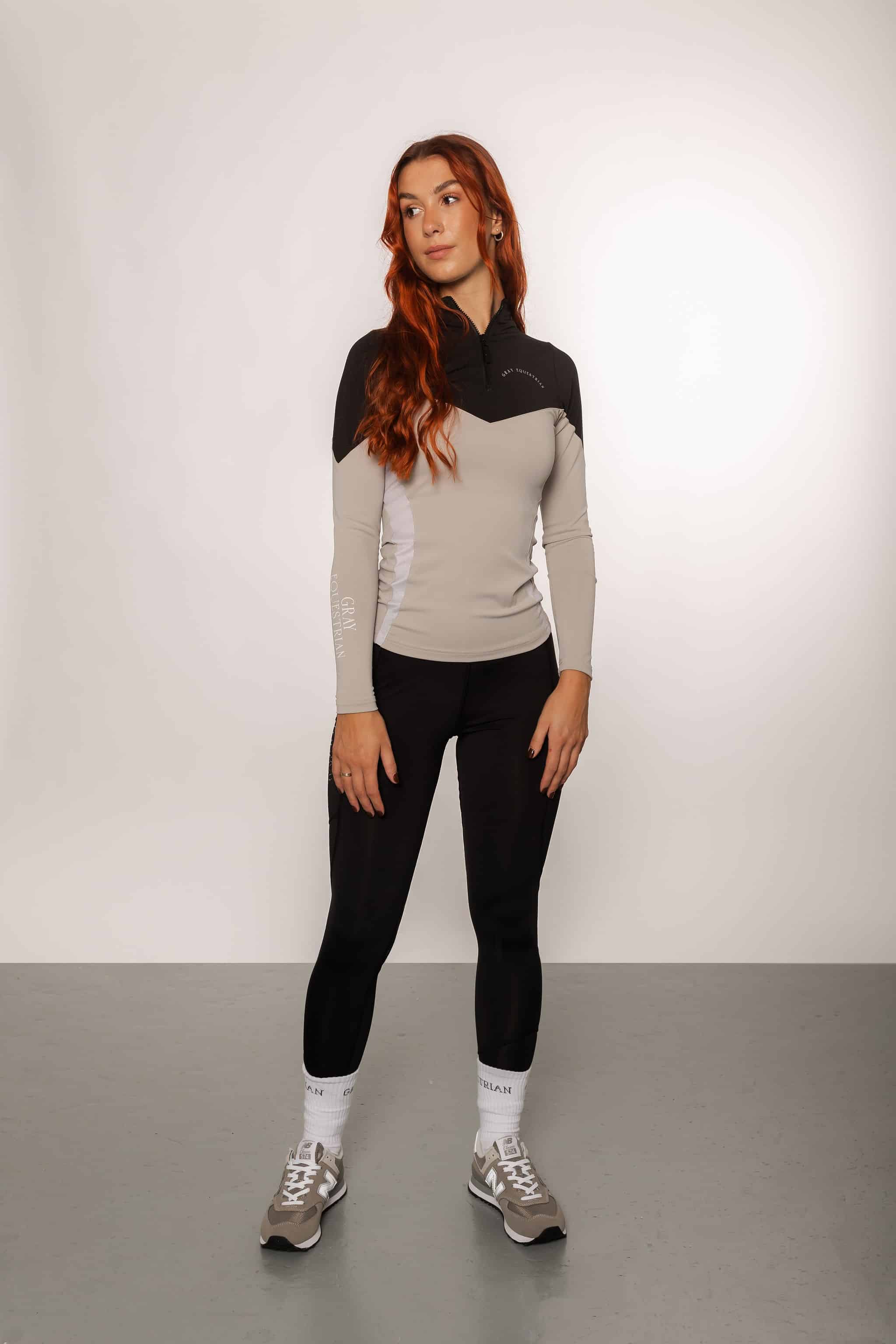 Red haired model wearing our long-sleeved black and grey two toned base layer and black equestrian leggings.