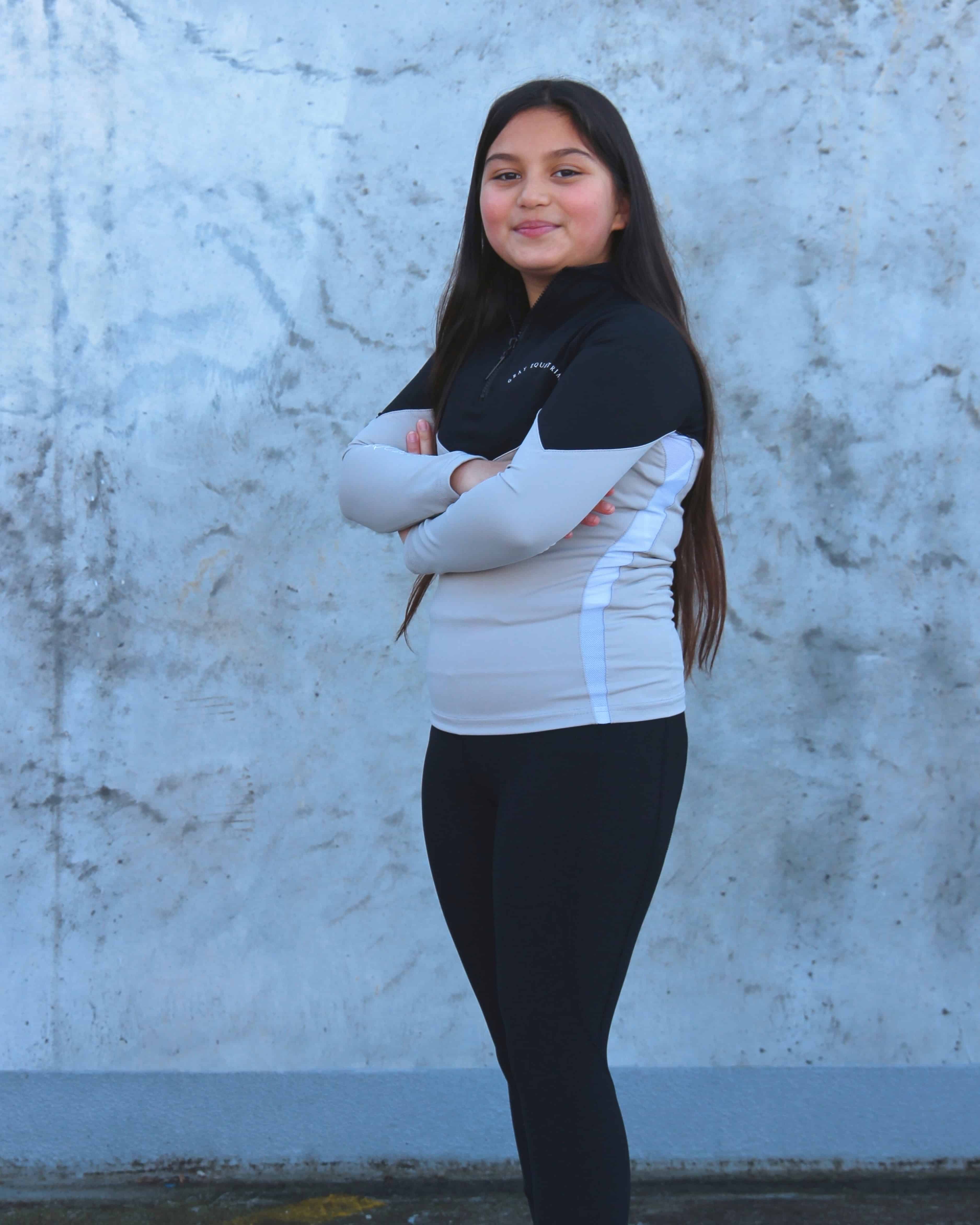 Our child model wearing our black and grey two toned base layer and black riding leggings.