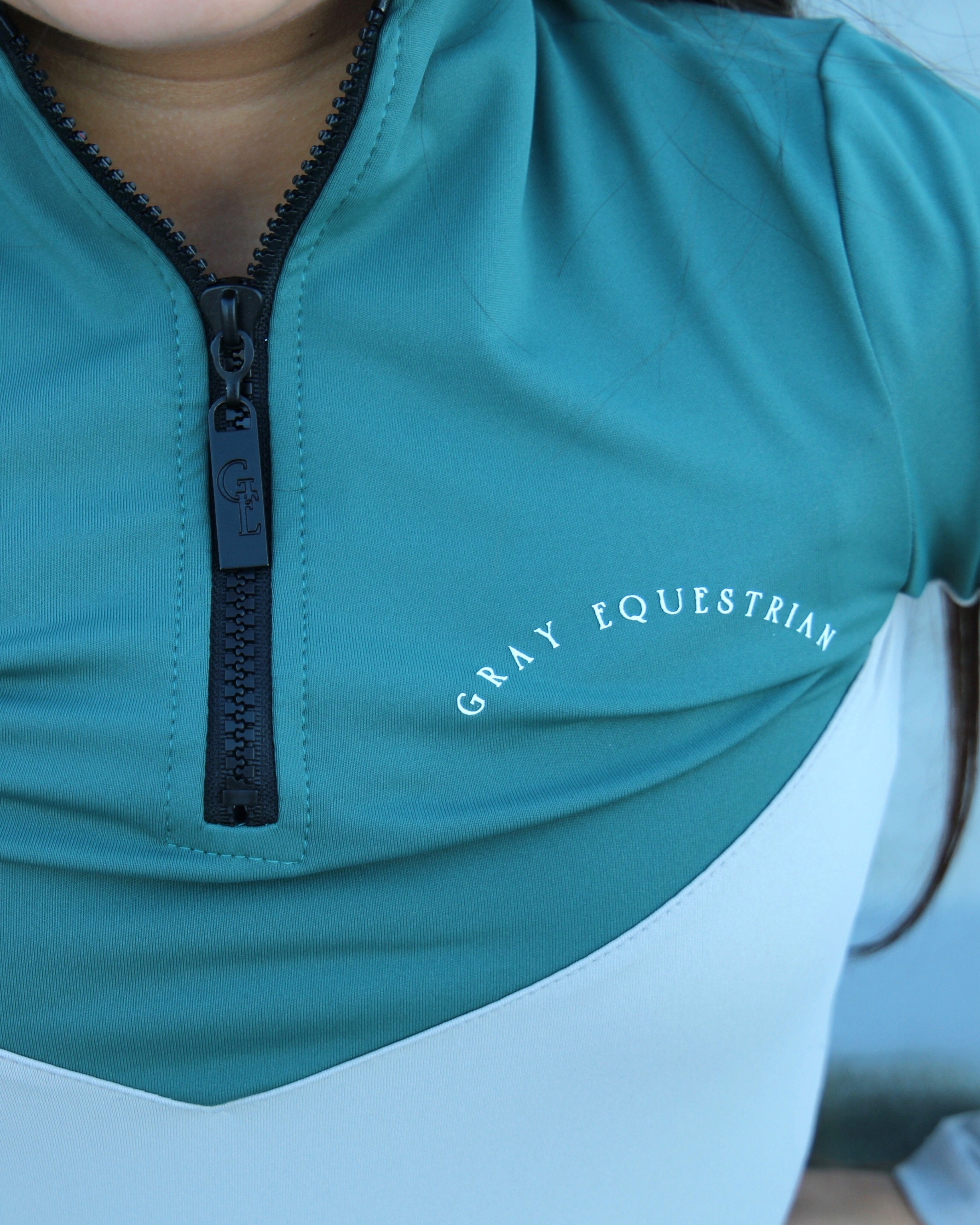 A child model wearing our our green and grey base layer with black leggings.