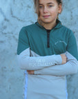 A child model wearing our our green and grey base layer with black leggings.