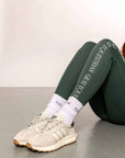 A close up of our green renew riding leggings and white performance socks.
