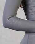 A close up of the minimal Grey Equestrian branding on the sleeve of our grey base layer.