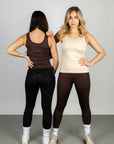Two models standing next to each other. The model on the left is wearing our brown renew vest and black riding leggings with full non slip seat. The model on the right is wearing our nude renew vest and brown riding leggings.