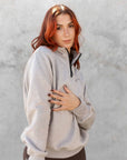 A model wearing our taupe grey 1/4 zip sweatshirt and green riding leggings.