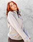 A model wearing our taupe grey 1/4 zip sweatshirt and green riding leggings.