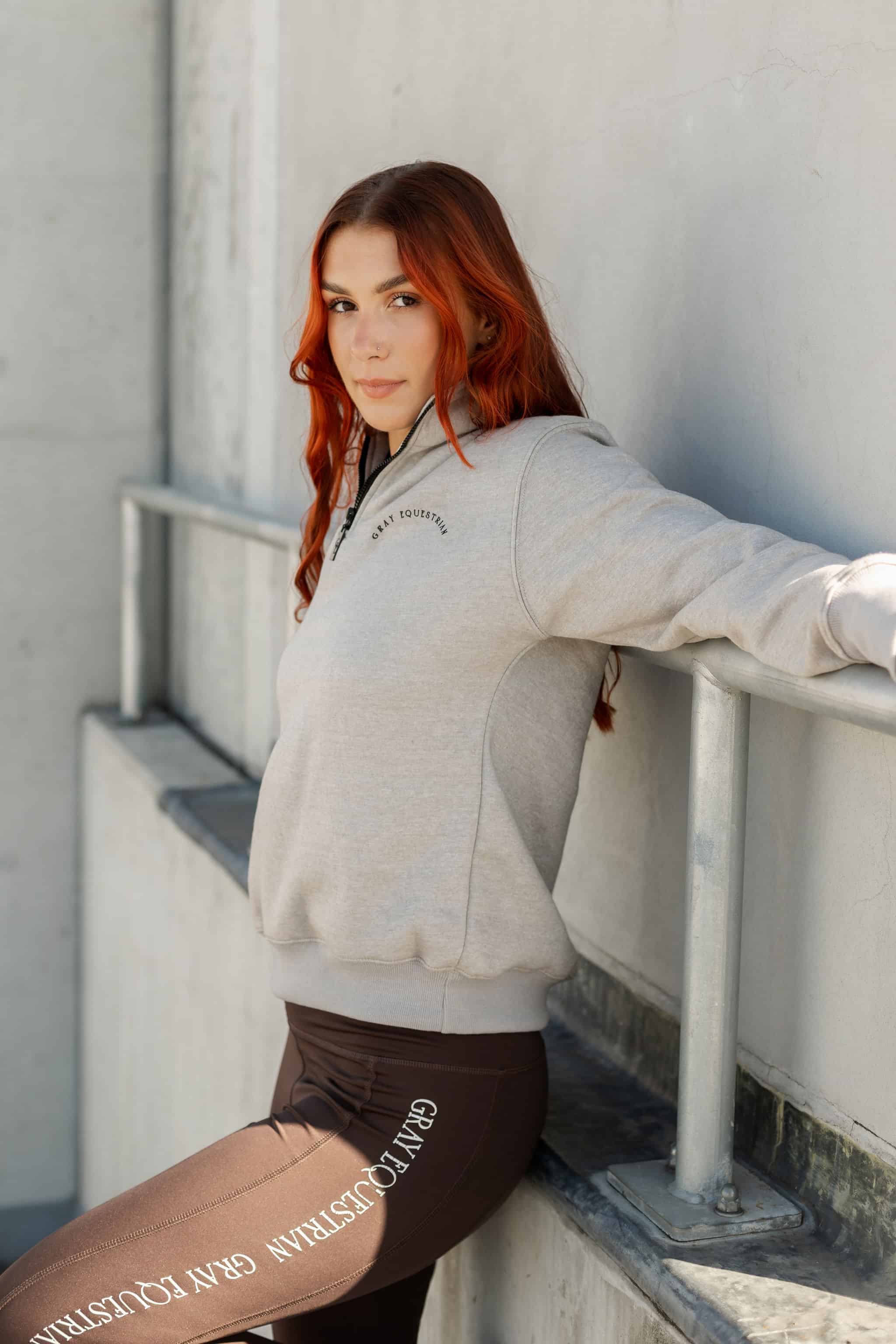 A model wearing our taupe grey 1/4 zip sweatshirt and green riding leggings.