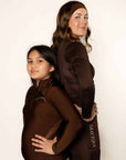 Young rider and adult rider wearing brown fleece lined base layer for horse riders.