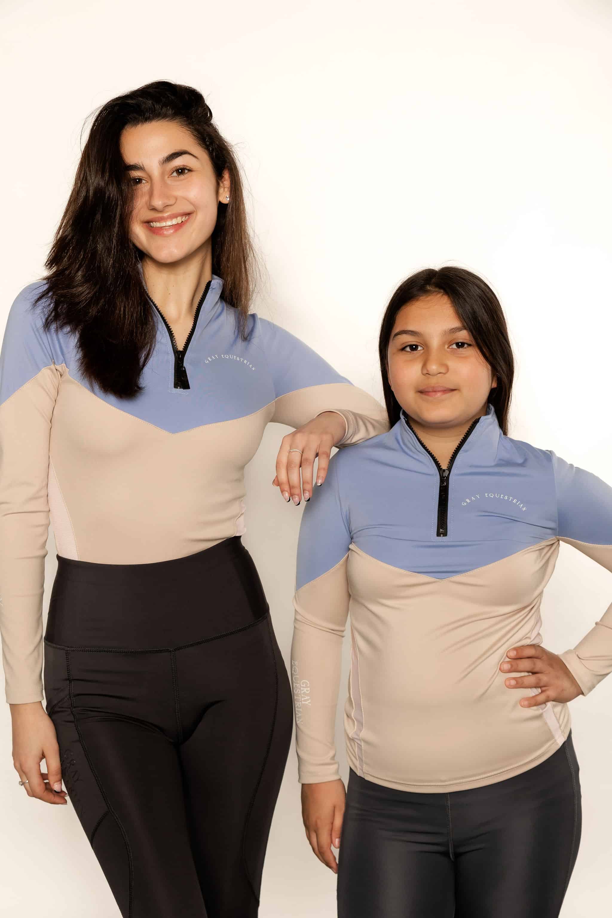 Adult rider and child rider wearing two tone base layer in blue and beige.