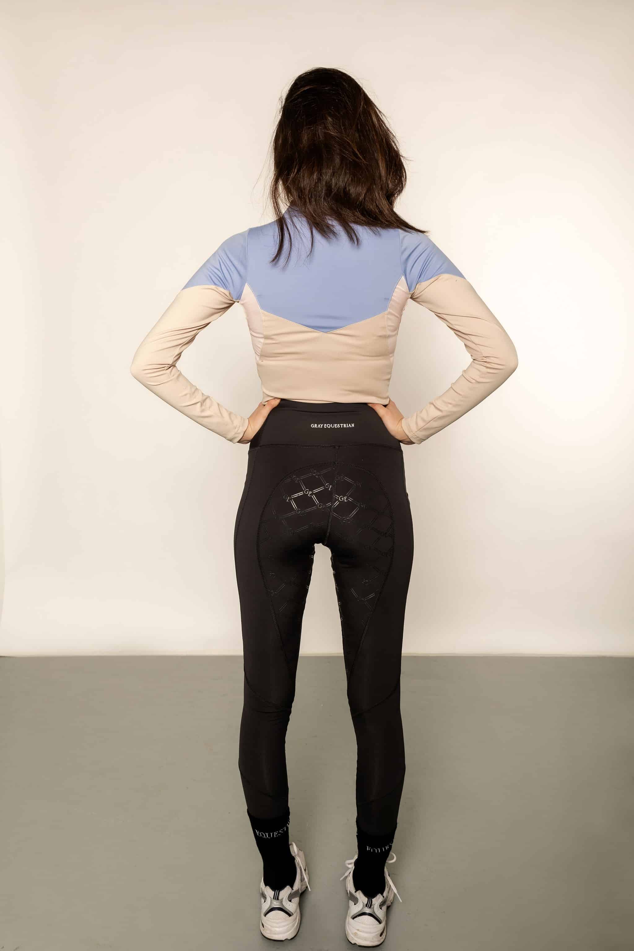 The behind of a blue and beige base layer with black leggings.