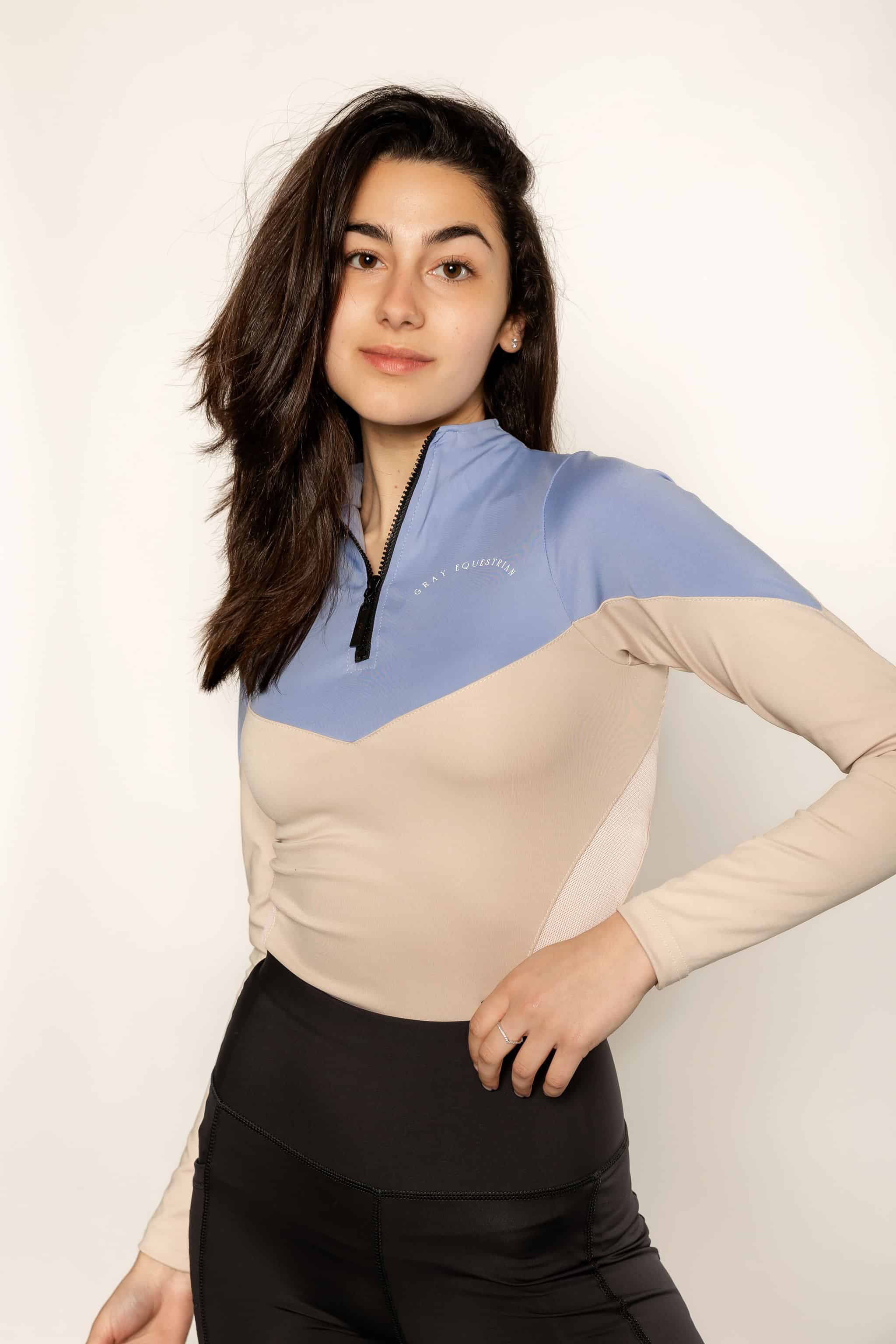 Model wearing a two tone equestrian base layer with 1/4 zip detail and mesh side panels.