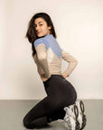 Model leaning down wearing blue & beige base layer with with black leggings.