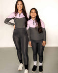 Adult and young rider model wearing charcoal grey riding leggings with pink and grey base layer top.