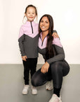 Young rider model and Model wearing charcoal grey riding leggings with pink and grey base layer top.
