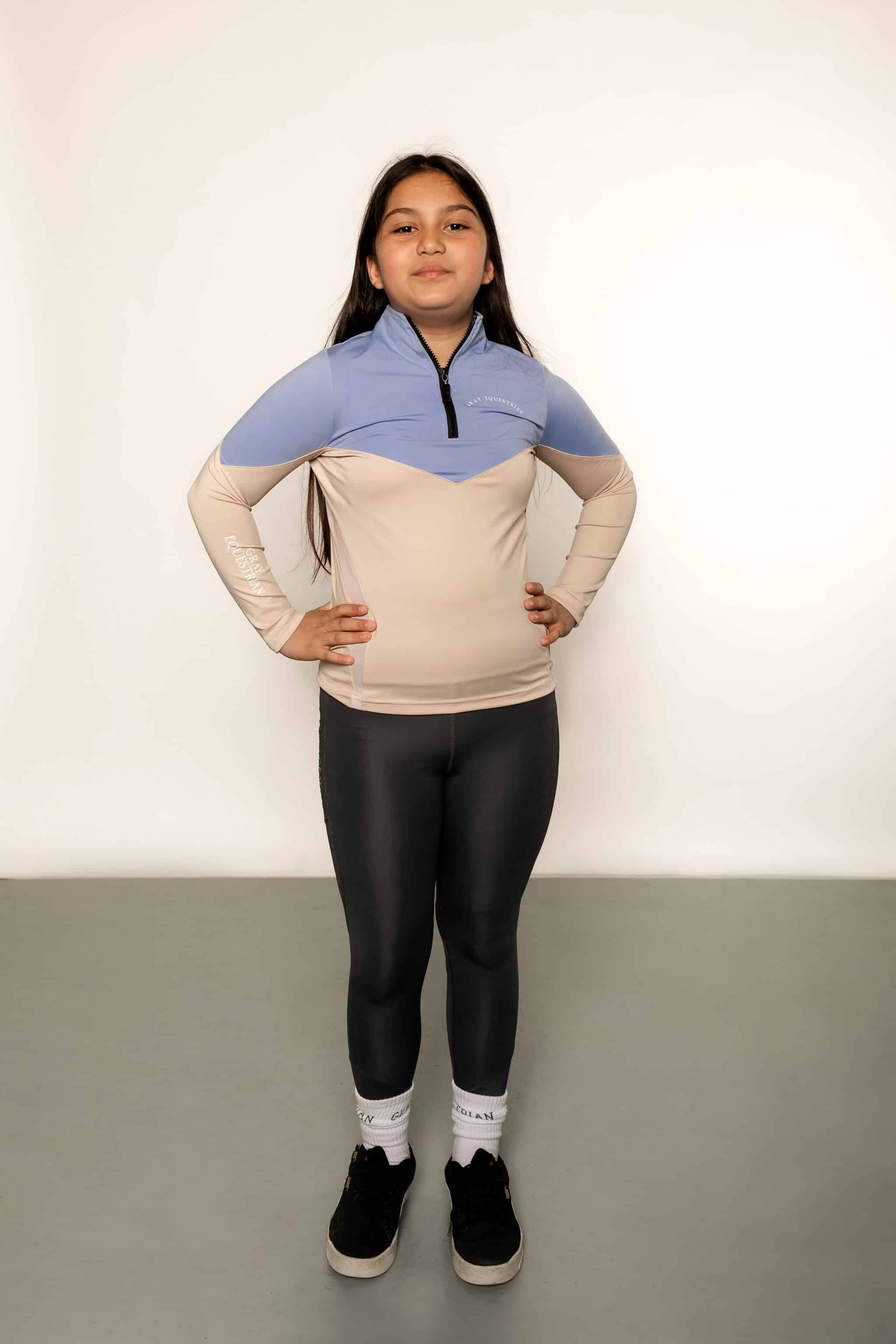 Young rider aged 12 wearing blue and beige base layer with black leggings