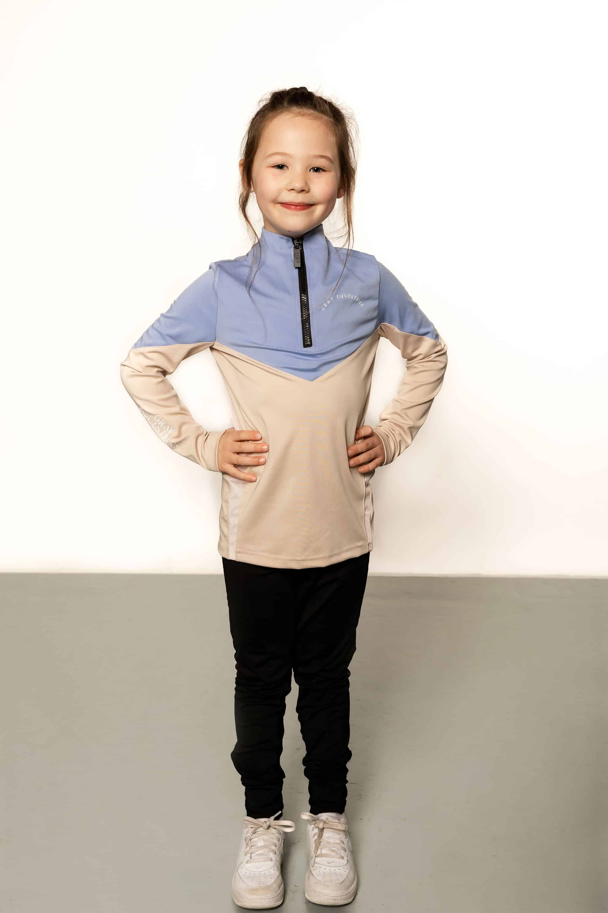 Young rider aged 7 wearing blue and beige base layer with black leggings