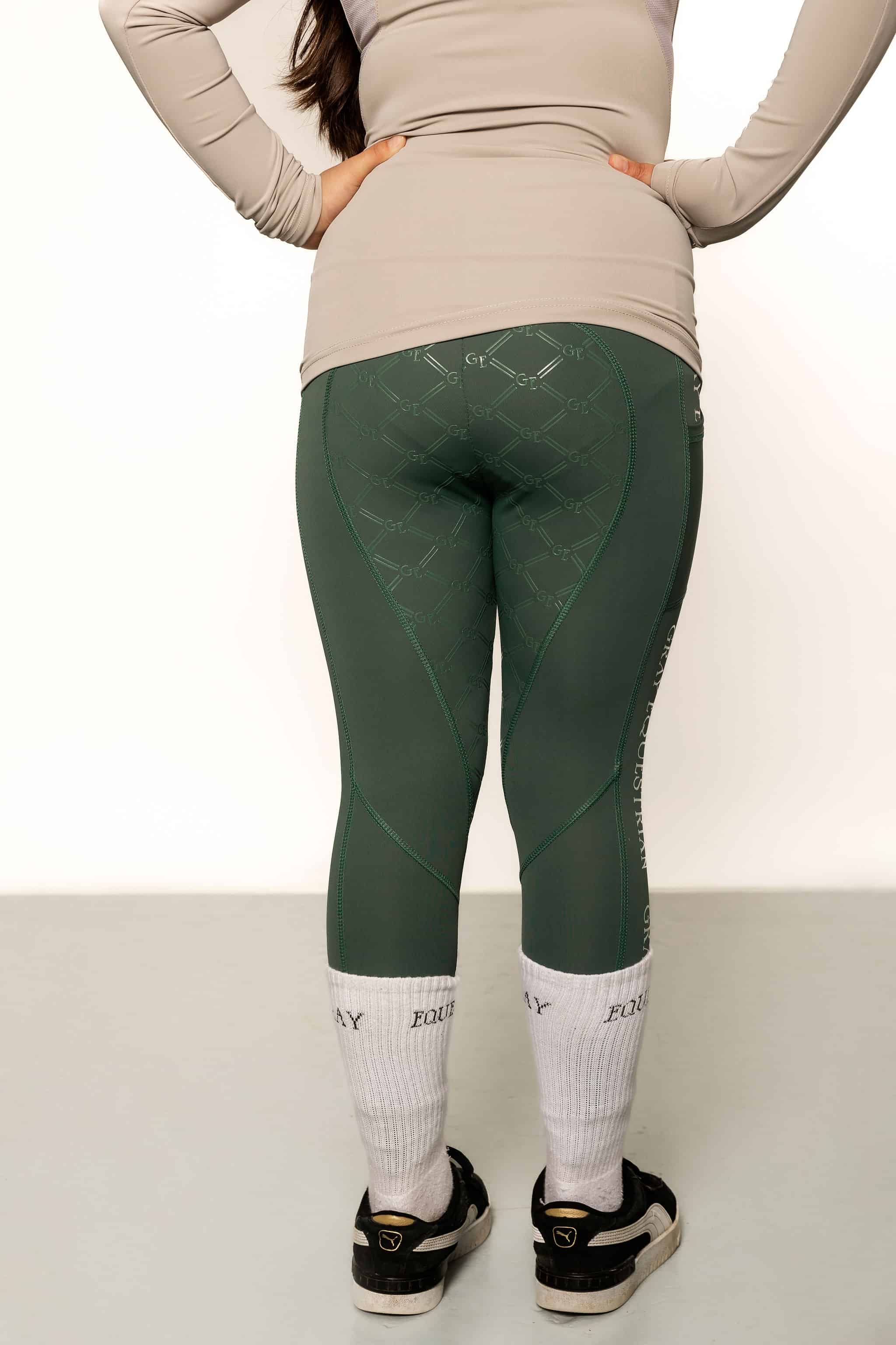 A child model wearing our green renew riding leggings.
