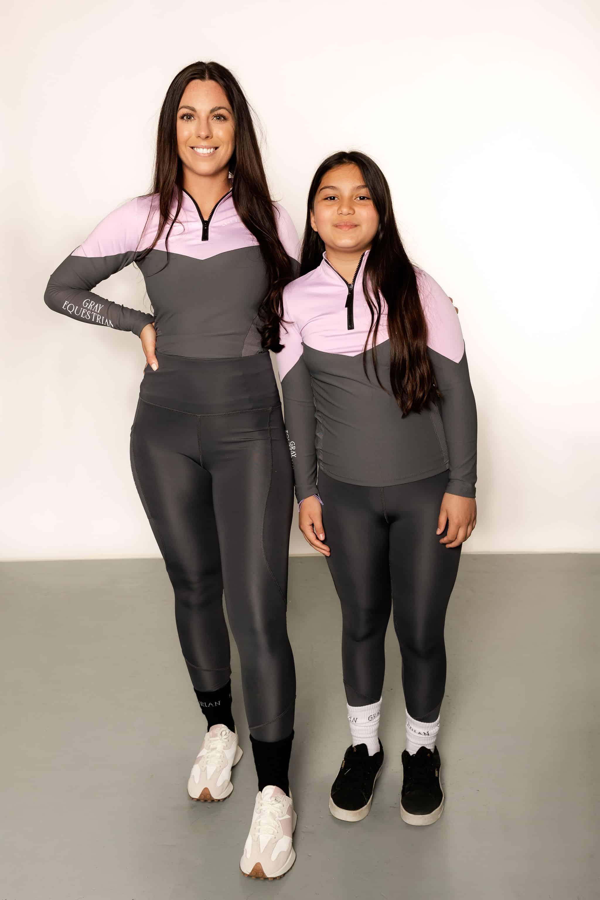 Young rider wearing lilac and grey base layer with adult rider matching