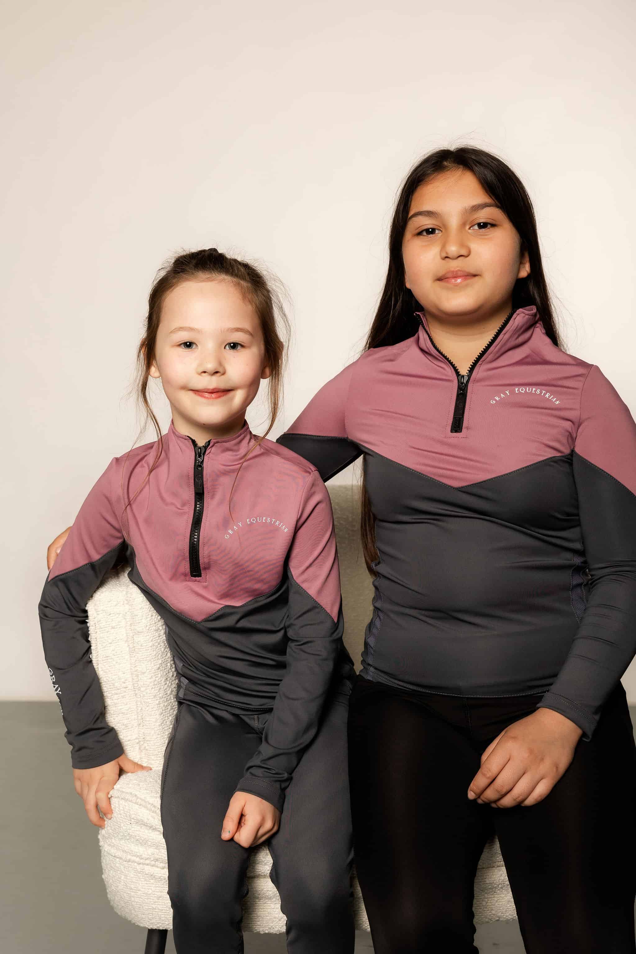 Two young riders wearing grey and pink base layers