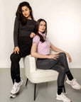 Two models wearing grey leggings and lilac top and black leggings and grey top.