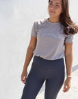 Brunette model wearing grey cotton t shirt with charcoal grey leggings.