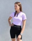 Brunette model wearing lilac base layer with black riding shorts